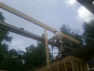 Carpenter setting a ridge beam over a new addition frame — Ice Dam Removal by Roofing Brothers in Pauls Valley