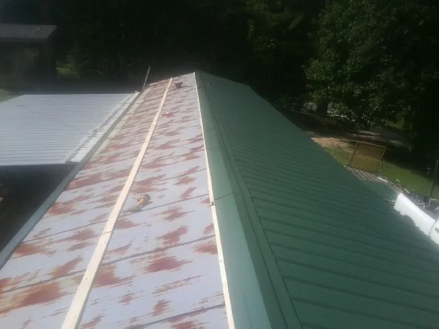 Old rusted panels beside newly installed green metal roofing — Wind Damage Roof Repair by Roofing Brothers in Pauls Valley