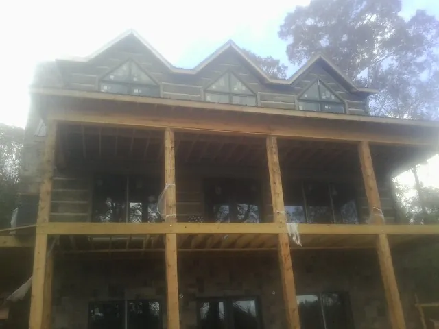 Dormers and porch framing on a large log home under construction — Roof Coating work by our crew in Pauls Valley