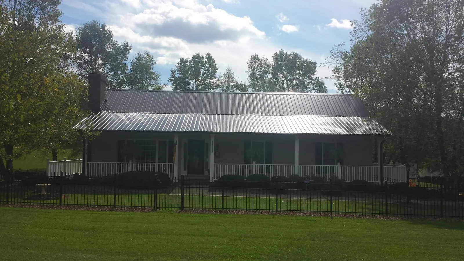 Gray metal roof on a brick ranch with a full width front porch — Gutter Guard Installation work by our crew in Pauls Valley