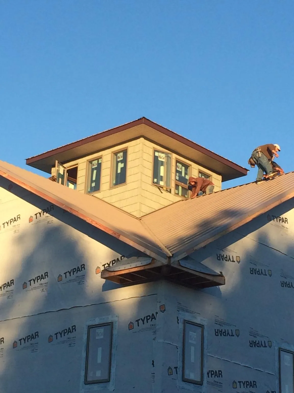 Roofers working around a rooftop cupola on a new metal roof at sunset — Roof Waterproofing in Pauls Valley by Roofing Brothers